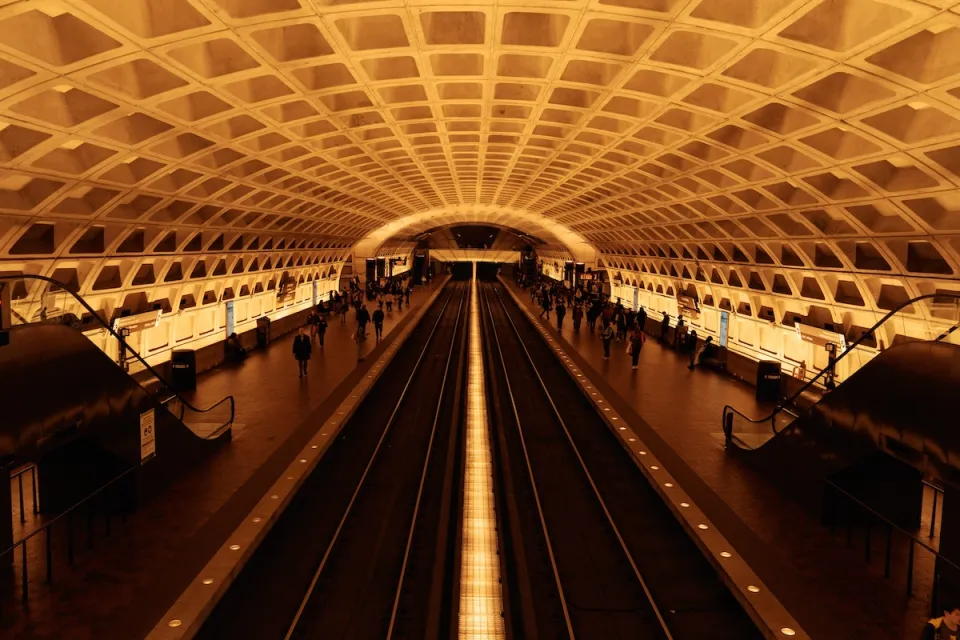 View of expansive subway station with curved roof and passengers waiting for trains in Washington, D.C.